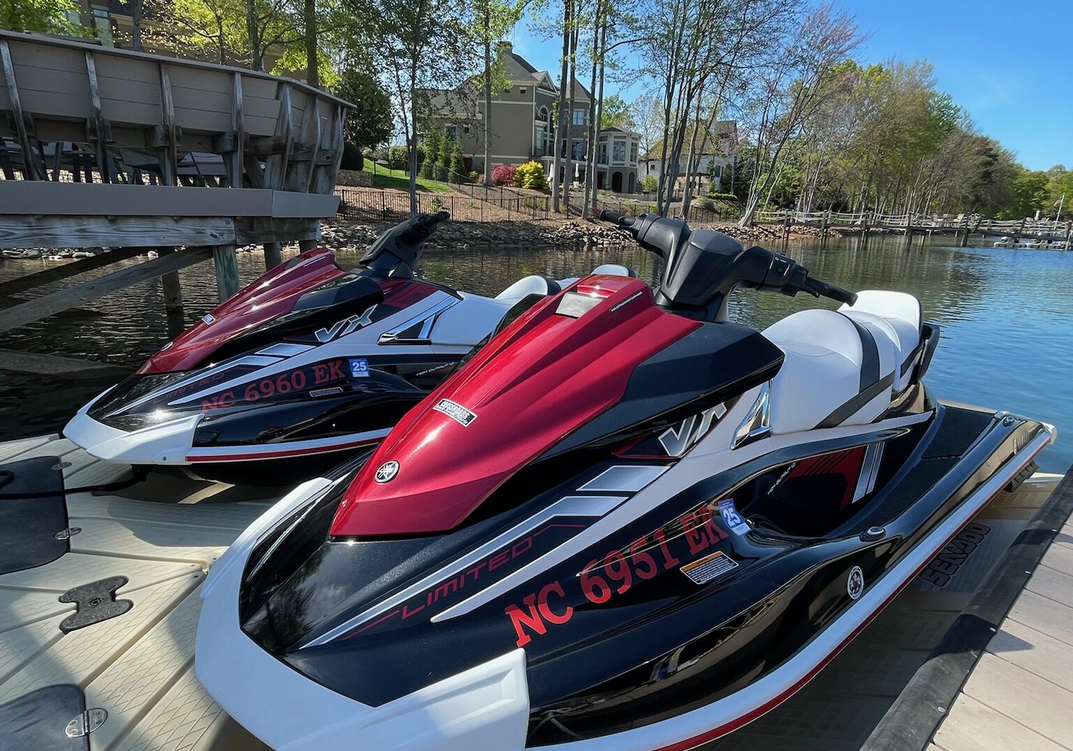 Pair of luxury jet skis docked at Lake Norman, NC, with glossy red and black finishes after premium marine detailing services.